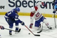 Tampa Bay Lightning center Brayden Point (21) and Montreal Canadiens center Nick Suzuki (14) play the puck during the second period in Game 1 of the NHL hockey Stanley Cup finals, Monday, June 28, 2021, in Tampa, Fla. (AP Photo/Gerry Broome)