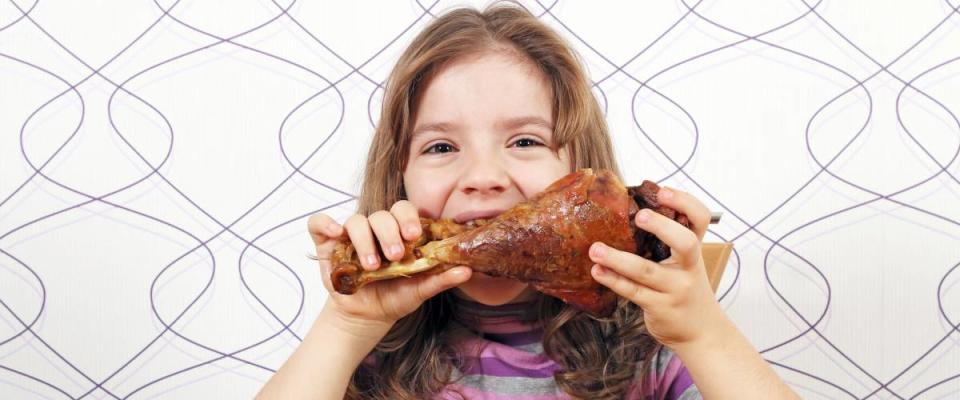 hungry little girl eating big turkey drumstick