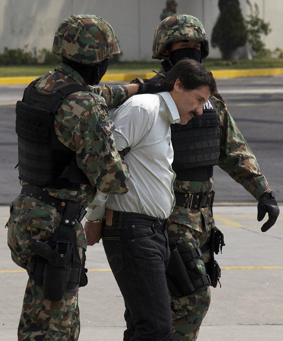 Joaquín "El Chapo" Guzmán, líder del Cártel de Sinaloa, es escoltado hacia un helicóptero con las manos esposadas por infantes de Marina mexicanos en un hangar de la Armada en la Ciudad de México, el sábado 22 de febrero de 2014. (Foto AP/Eduardo Verdugo)