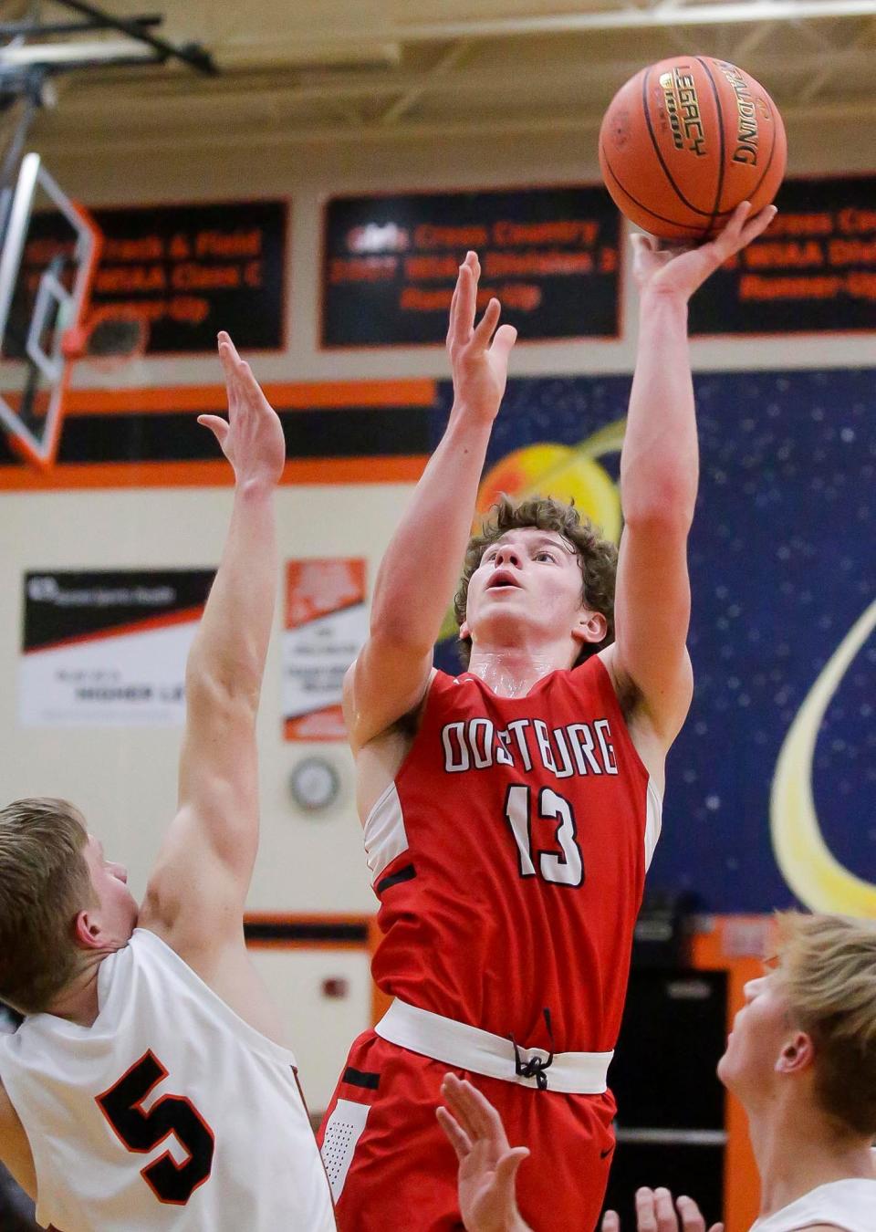 Oostburg’s Jamison Zavatchin (13) launches a shot against Cedar Grove-Belgium’s Caleb Beightol (5), Thursday, February 2, 2023, in Cedar Grove, Wis.