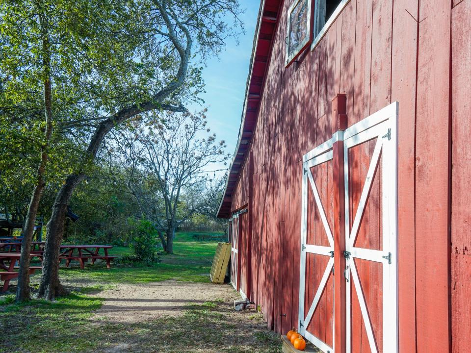 The barn house is on the right and trees are on the left on a clear day