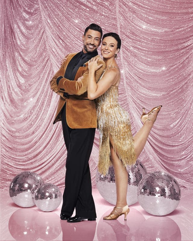 Giovanni Pernice and Amanda Abbington pose against a pink backdrop as they smile to the camera