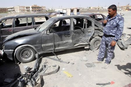A policeman inspects damage caused to other vehicles after a car bomb attack near a police station, south of the city of Kirkuk July 10, 2014. At least eight people were wounded in the attack, police said. REUTERS/Ako Rasheed