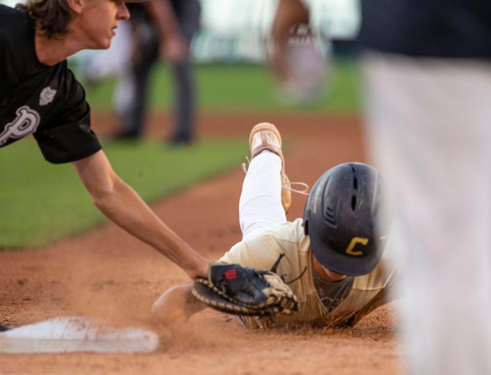 Max Sanders tags out Chris Klung at first in the state championship baseball game between the Penn Kingsman and Cathedral Irish on Saturday, June 18, 2022 at Victory Field in Indianapolis. 