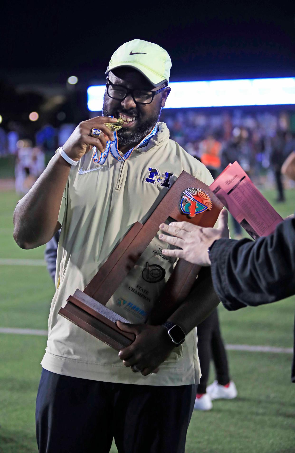 Mainland coach Travis Roland accepts the trophy after the Bucs claimed a 21-19 win over St. Augustine in the Class 3S state championship game on Thursday in Tallahassee.