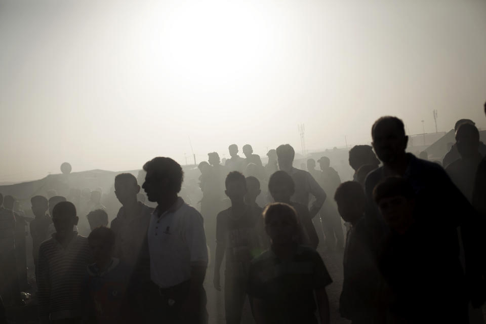 FILE - In this Tuesday, Oct. 22, 2013 file photo, dozens of Syrian refugees watch a tent and a trailer on fire at the Zaatari Refugee camp near the Syrian border in Jordan. Syria’s uprising was not destined to be quick. Instead, the largely peaceful protest movement that spread across the nation slowly turned into an armed insurgency and eventually a full-blown civil war. More than 130,000 people have been killed, and more than 2 million more have fled the country. Nearly three years after the crisis began, Syria's government and opposition are set to meet in Geneva this week for the first direct talks aimed at ending the conflict. (AP Photo/Manu Brabo, File)