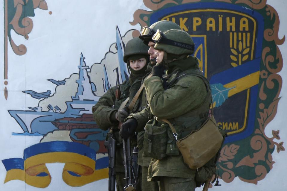 Military personnel, believed to be Russian servicemen, stand guard outside the territory of a Ukrainian military unit in the village of Perevalnoye outside Simferopol