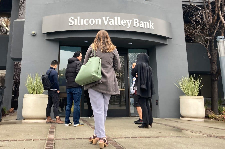 People stand outside of an entrance to Silicon Valley Bank in Santa Clara, Calif., Friday, March 10, 2023. (AP Photo/Jeff Chiu, File)