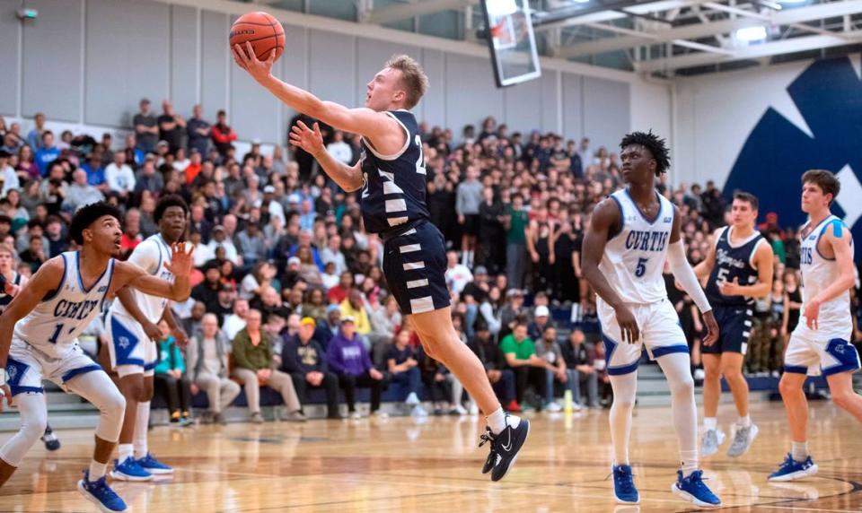 Olympia’s Parker Gerrits slips to the basket between Curtis defenders Cinque Maxwell and Zoom Dialo (5) during Saturday night’s 4A SPSL boys basketball tournament championship game at Tacoma Community College in Tacoma, Washington, on Feb. 4, 2023.