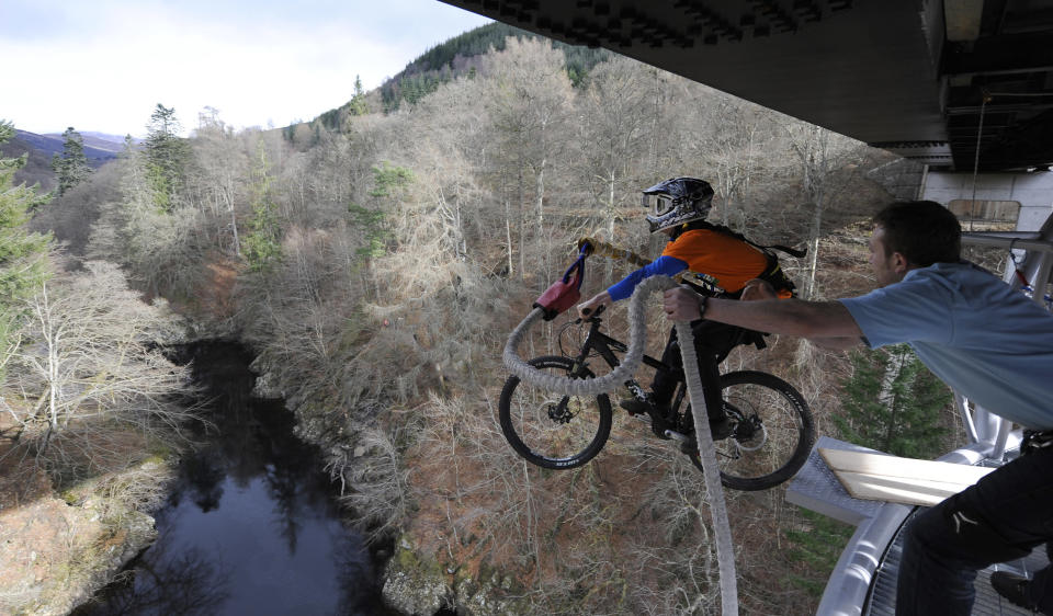 Cyclist Adam Flint, attached to a bungee rope, pedals off the Garry Bridge near Pitlochry, in Scotland February 28, 2012. The stunt was aimed to promote cycling in Highland Perthshire. REUTERS/Russell Cheyne