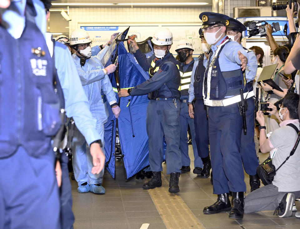 Rescuers carry a stretcher, believed to be carrying an injured passenger at Soshigaya Okura Station after stabbing on a commuter train, in Tokyo Friday night, Aug. 6, 2021. A man with a knife attacked 10 passengers on a commuter train in Tokyo on Friday and was arrested by police after fleeing, fire department officials and news reports said. (Kyodo News via AP)
