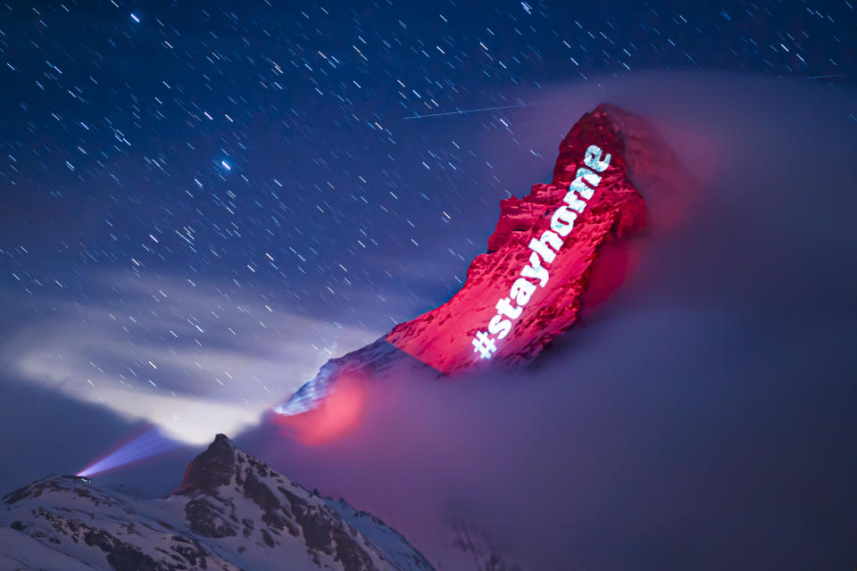 The iconic Matterhorn mountain is illuminated by Swiss light artist Gerry Hofstetter aiming to send messages of hope, support and solidarity to the ones sufferings from the global coronavirus disease, COVID-19, pandemic in the alpine resort of Zermatt, Switzerland, Thursday, March 26, 2020. The new coronavirus causes mild or moderate symptoms for most people, but for some, especially older adults and people with existing health problems, it can cause more severe illness or death. (Valentin Flauraud/Keystone via AP)