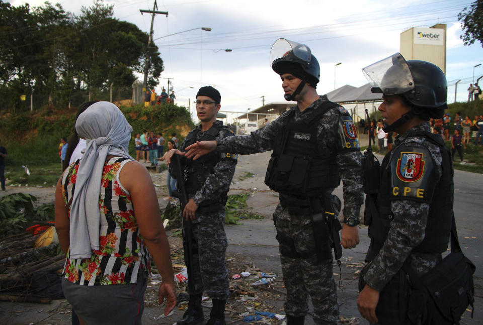 A woman asks police officers for more information outside the Anisio Jobim Prison Complex in Manaus, Amazonas state, Brazil, Monday, May 27, 2019. Brazilian authorities said 42 inmates were killed at three different prisons in the capital of the northern state of Amazonas, a day after 15 prisoners died in a riot at a fourth prison in the city. (AP Photo/Edmar Barros)