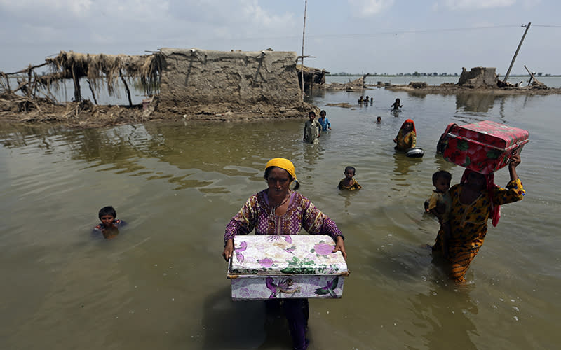 Women carry belongings salvaged from their flooded home after monsoon rains