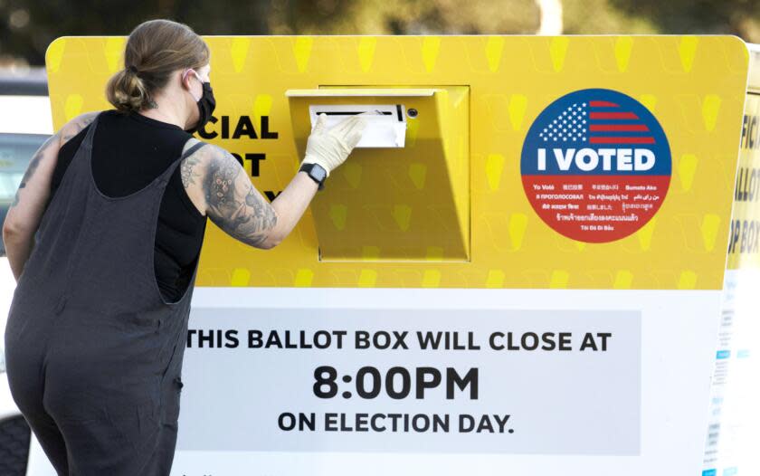 =A woman drops off her ballot at an Official Ballot Drop Box located near the Rose Bowl in Pasadena, CA October 13, 2020. =