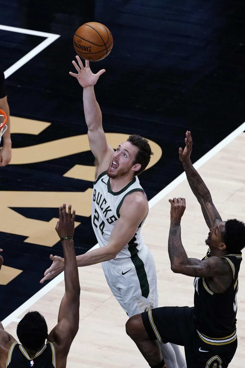 Milwaukee Bucks guard Pat Connaughton (24) goes in for a basket as Atlanta Hawks guard Lou Williams, right, defends during the first half of an NBA basketball game Thursday, April 15, 2021, in Atlanta. (AP Photo/John Bazemore)