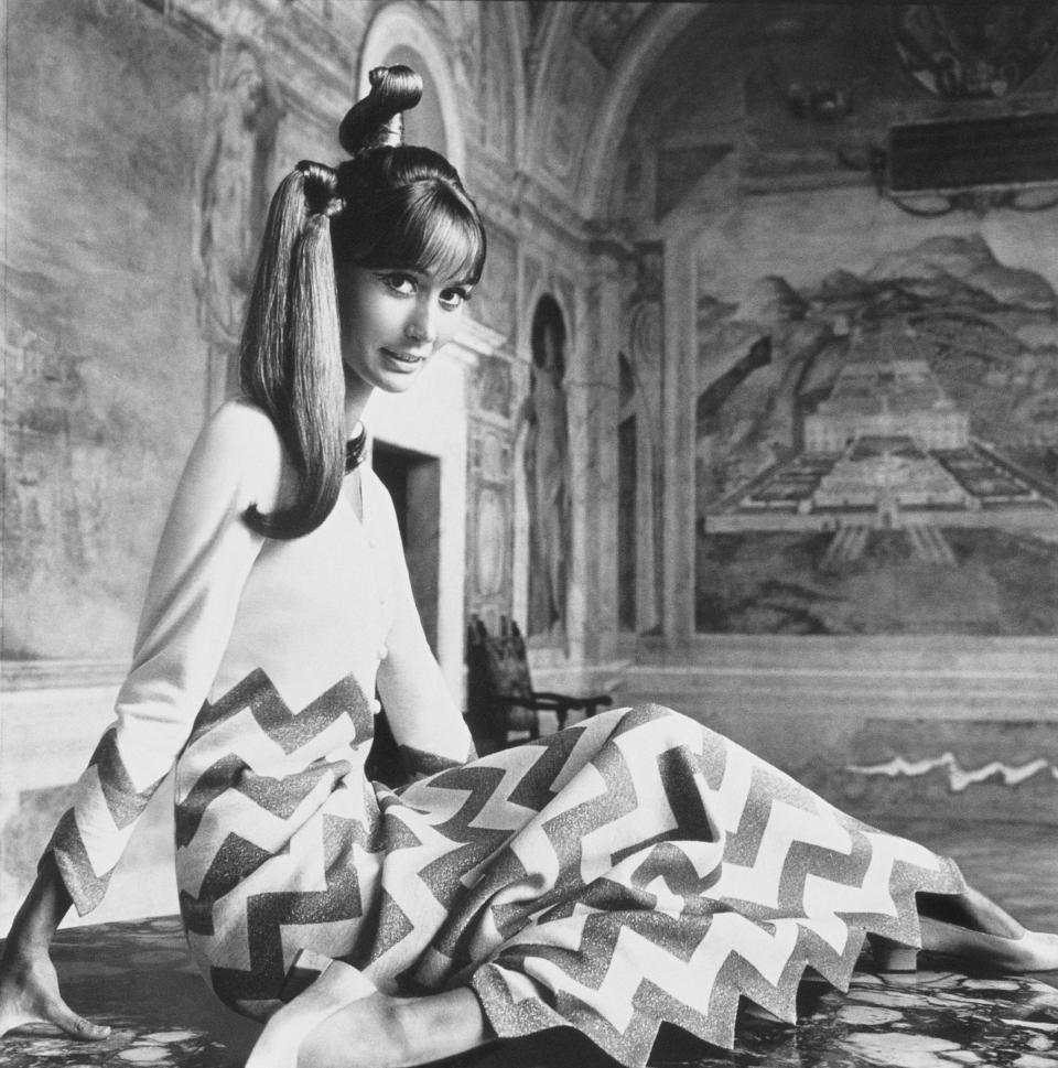 Madame Philippe Leroy (Silvia Tortora) in “zigzag gold lamé stripes tinseling white jersey—to pointed wrist, pointed hem. Evening dress by Mila Schön, in Agnona fabric designed by Mila Schön.”​