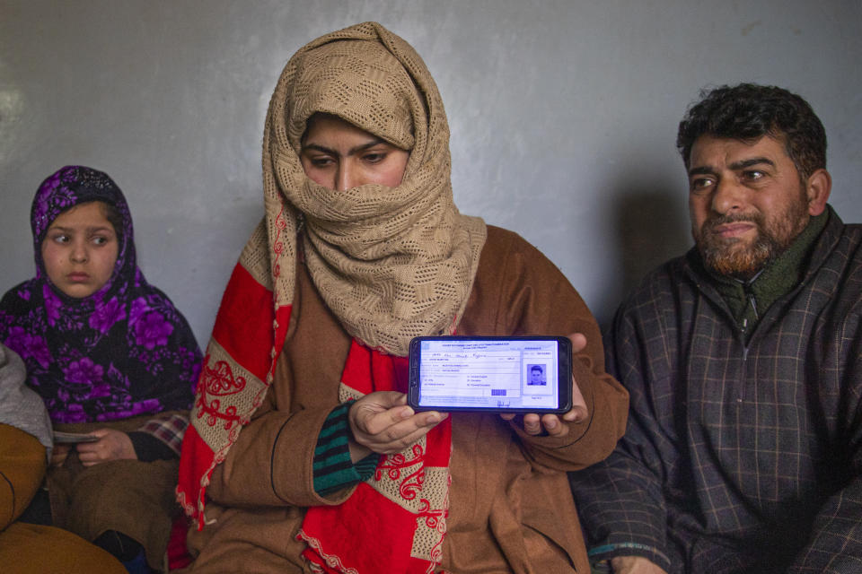 Zarqa Mushtaq, center, shows on a mobile phone the 11th grade examination slip of her 16 -year old brother Athar Mushtaq, as her father Mushtaq Ahmad Wani, looks on while talking to the Associated Press in Bellow, south of Srinagar, Indian controlled Kashmir, Tuesday, Jan. 5, 2021. On the last week of 2020, Indian government forces killed Athar and two other young men during a controversial gunfight on the outskirts of the Indian-controlled Kashmir’s main city. Police did not call them anti-India militants but “hardcore associates of terrorists." They later buried them at a graveyard in a remote mountainous tourist resort miles away from their ancestral villages. Athar was the latest Kashmiri to be buried in a far-off graveyard after Indian authorities in a new controversial policy in 2020 started to consign blood-soaked bodies of scores of Kashmiri suspected rebels to unmarked graves, denying the mourning families a proper funeral and a burial. (AP Photo/ Dar Yasin)