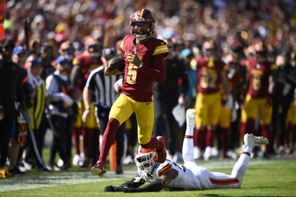 Washington Commanders quarterback Jayden Daniels (5) runs past Cleveland Browns defensive end Ogbo Okoronkwo (54) during the first half of an NFL football game in Landover, Md., Sunday, Oct. 6, 2024. (AP Photo/Nick Wass)