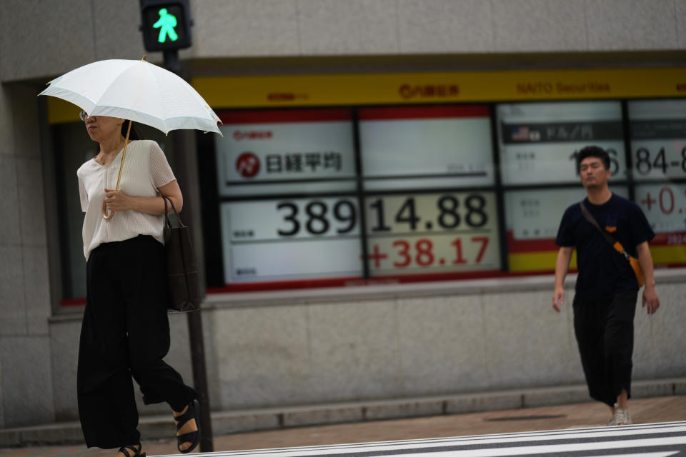 People walk past monitors showing Japan's Nikkei 225 index at a securities firm at the corner of an intersection in Tokyo, Thursday, June 13, 2024. (AP Photo/Hiro Komae)