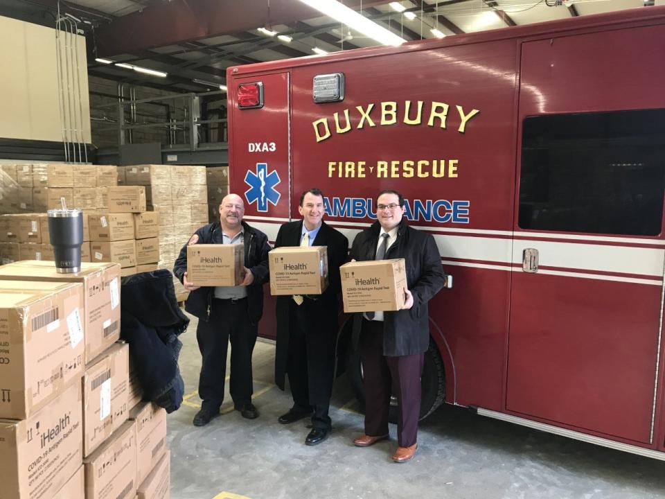 Duxbury Fire Capt. Brian Monahan (left), former state rep. Jim Cantwell and Plymouth County Commissioner Jared Valanzola hold cartons of rapid COVID-19 test kits. Duxbury received 5,580 kits, with two tests each.