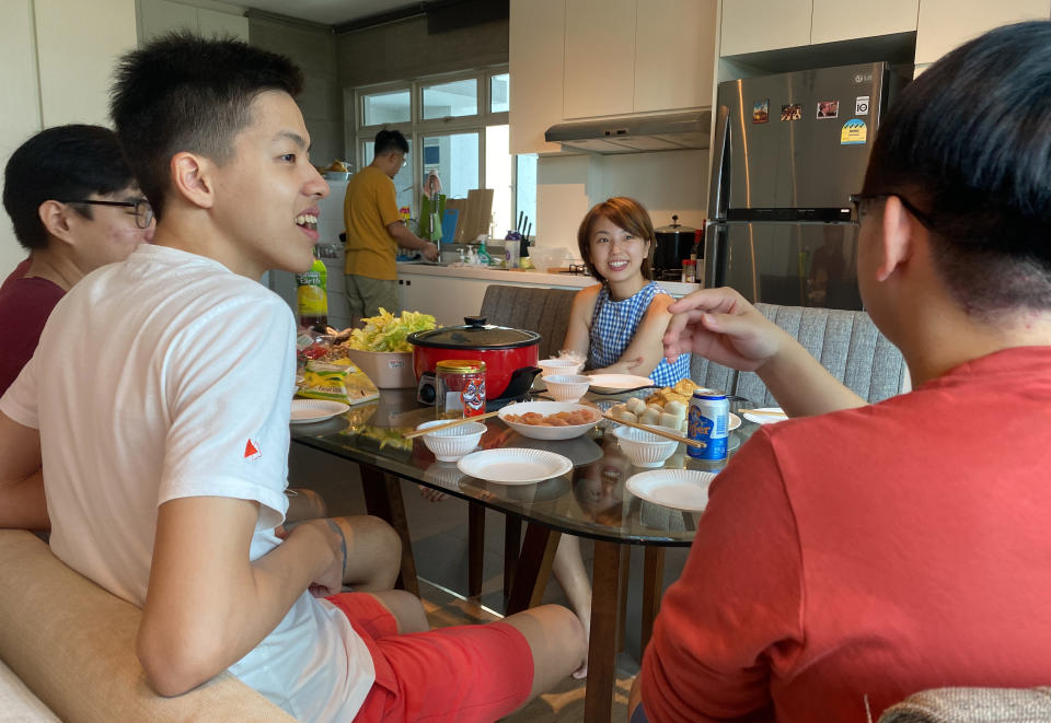 Chan Jit Yen smiles as she hosts Malaysian students, foreground, during a Lunar New Year hot pot lunch at her rented apartment in Singapore Saturday, Feb. 13, 2021. With Malaysian workers and students stranded in the city state over the Lunar New Year due to coronavirus travel restrictions, the Malaysian Association in Singapore has called on Malaysians to treat students to a meal. (AP Photo/Annabelle Liang)