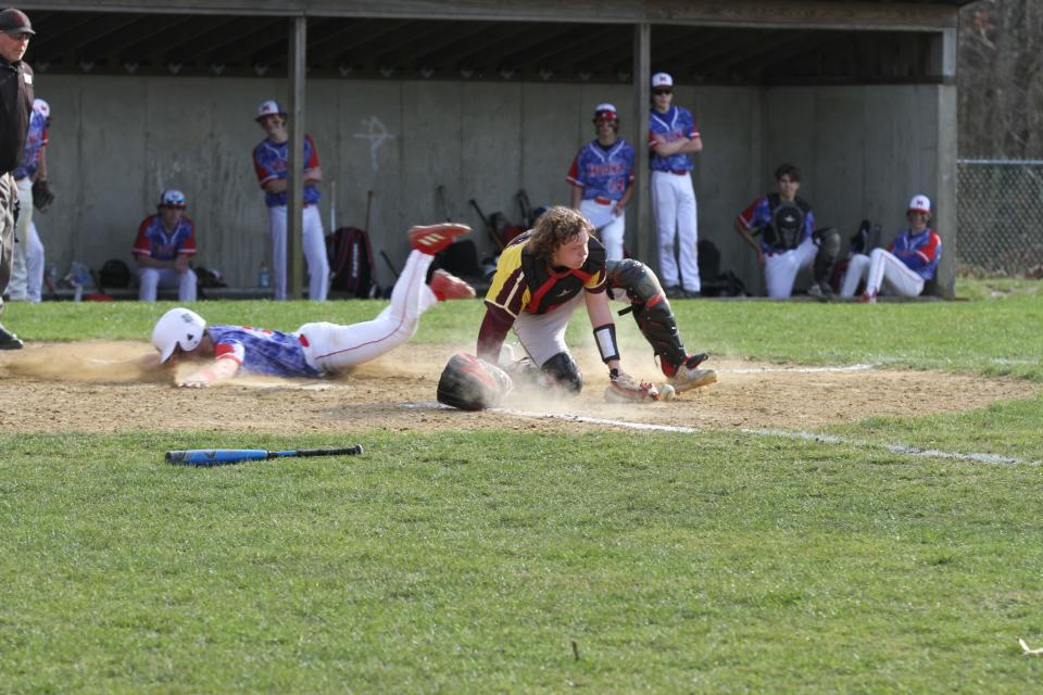 Tiverton High catcher Noah Mercer tries to retrieve the ball after blocking a low throw from an infielder as a Mount St. Charles runner dives head first safely home. The visiting Mounties topped the Tigers 11-4 in Tuesday's baseball game in Tiverton.