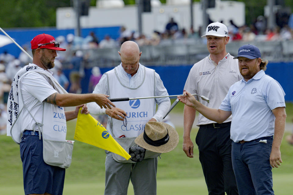 Zac Blair, right, and Patrick Fishburn, second from right, finish off their round on the 18th hole during the third round of the PGA Zurich Classic golf tournament at TPC Louisiana in Avondale, La., Saturday, April 27, 2024. (AP Photo/Matthew Hinton)