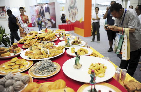 A visitor takes pictures at different types of food made of potatoes on display during the World Potato Congress on the outskirts of Beijing, China, July 28, 2015. REUTERS/Stringer