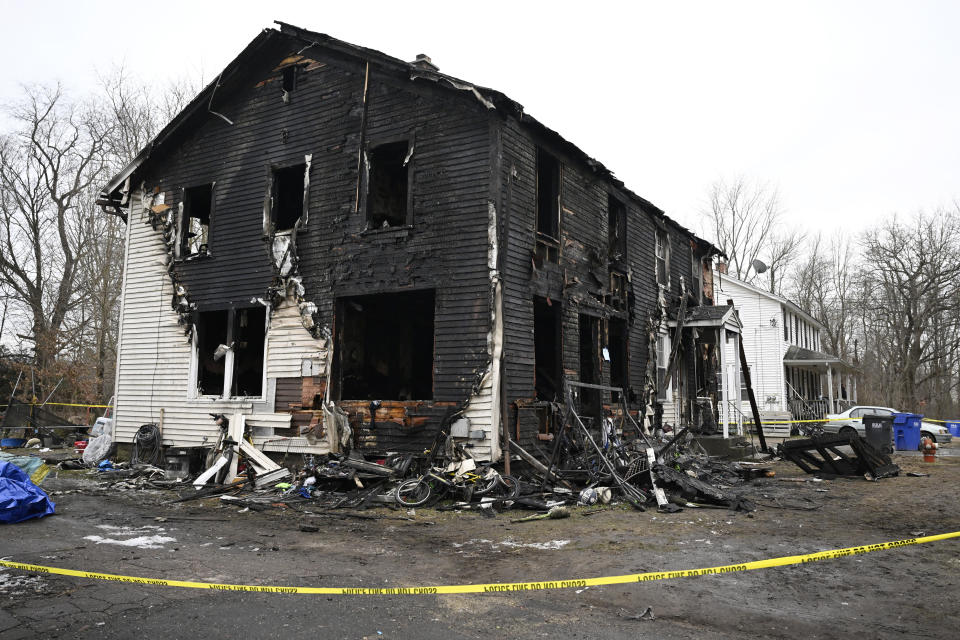 Charred siding and items are strewn about at a two-family home Wednesday, Jan. 3, 2024, in Somers, Conn., in the aftermath of a fatal fire. Four children died Tuesday night in a fire that broke out in the two-family home. The children, ages 5, 6, 8 and 12, were found inside the house where 11 people lived, fire and town officials said. (AP Photo/Jessica Hill)