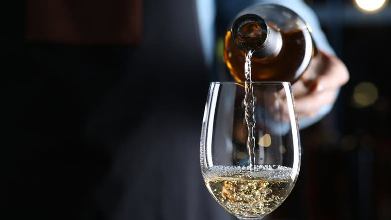 sommelier pouring white wine into glass