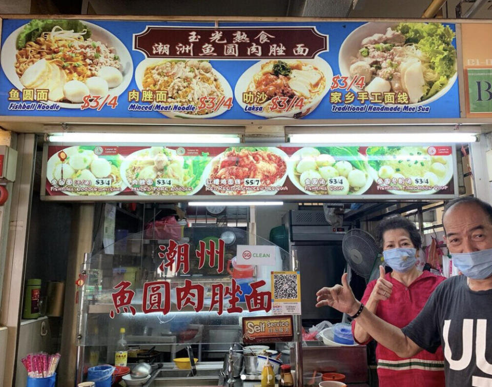 An elderly couple standing in front of their hawker stall