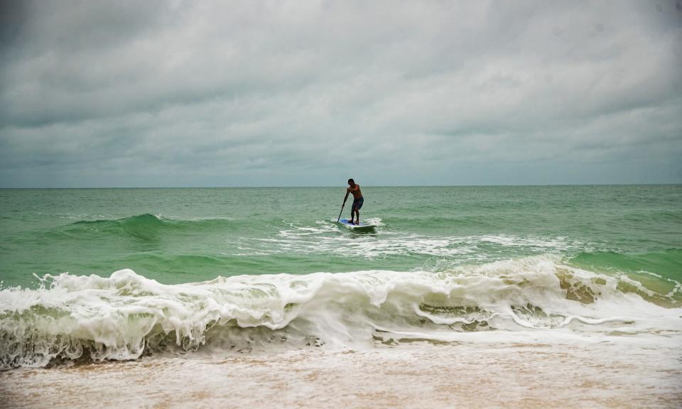 Dean McCallum surfs the waves on a stand up paddle board on the Gulf of Mexico on Bonita Beach as light rain falls on Friday, June 3, 2022.  A possible tropical depression/storm is heading towards Southwest Florida. 