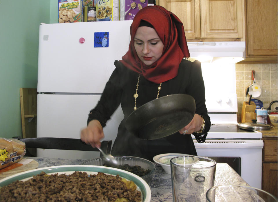 In this Aug. 5, 2019 photo, Hazar Mansour serves dinner to her family and a guest in their apartment in Rutland, Vt. She, her husband Hussam Alhallak, and their children fled the war in Syria in 2015 and are now rebuilding a life for themselves in Vermont. (AP Photo/Lisa Rathke)