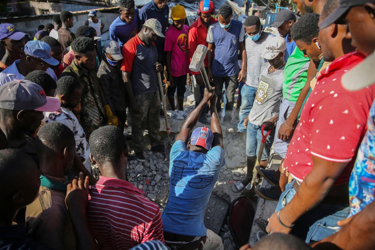 A man uses a sledgehammer to rescue people from the rubble of a home destroyed by an earthquake in Les Cayes, Haiti, Saturday, Aug. 14, 2021.