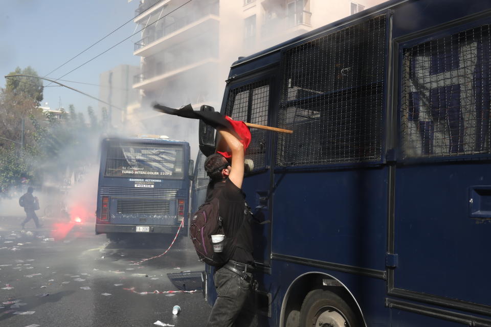 A protester tries to damage a police vehicle during scuffles in part of an anti-fascist rally, outside the courthouse in Athens, Wednesday, Oct. 7. The court has ruled the far-right Golden Dawn party was operating as a criminal organization, delivering landmark guilty verdicts in a politically charged five-year trial against dozens of defendants, including former lawmakers of what had become Greece's third largest party. (AP Photo/Yorgos Karahalis)