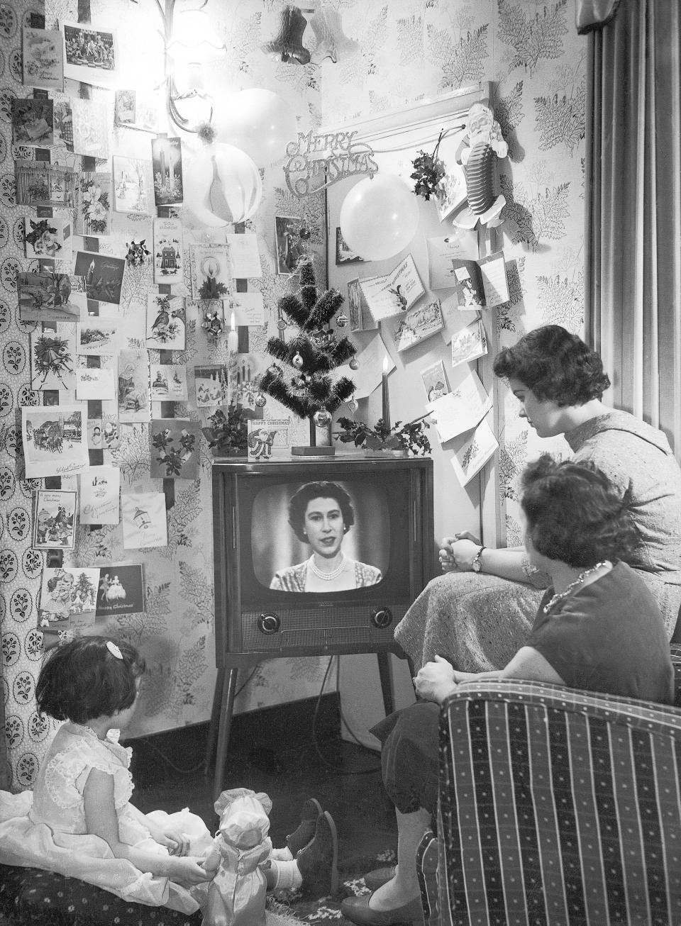 A family watch as Britain's Queen Elizabeth II makes her first televised Christmas broadcast, Dec. 25, 1957. (AP Photo/Sidney Smart)