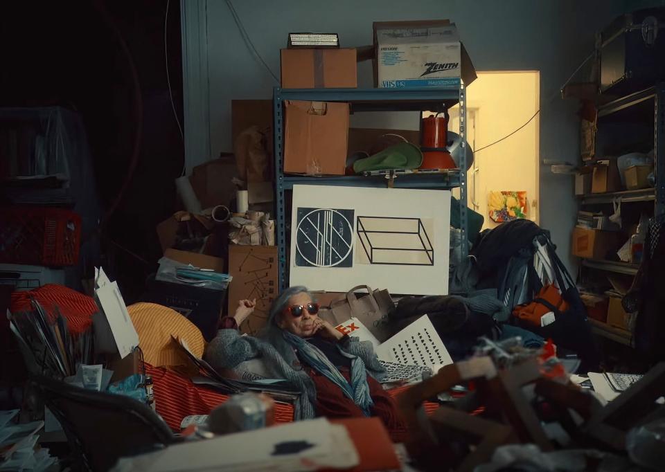 A resident sits in her cluttered apartment