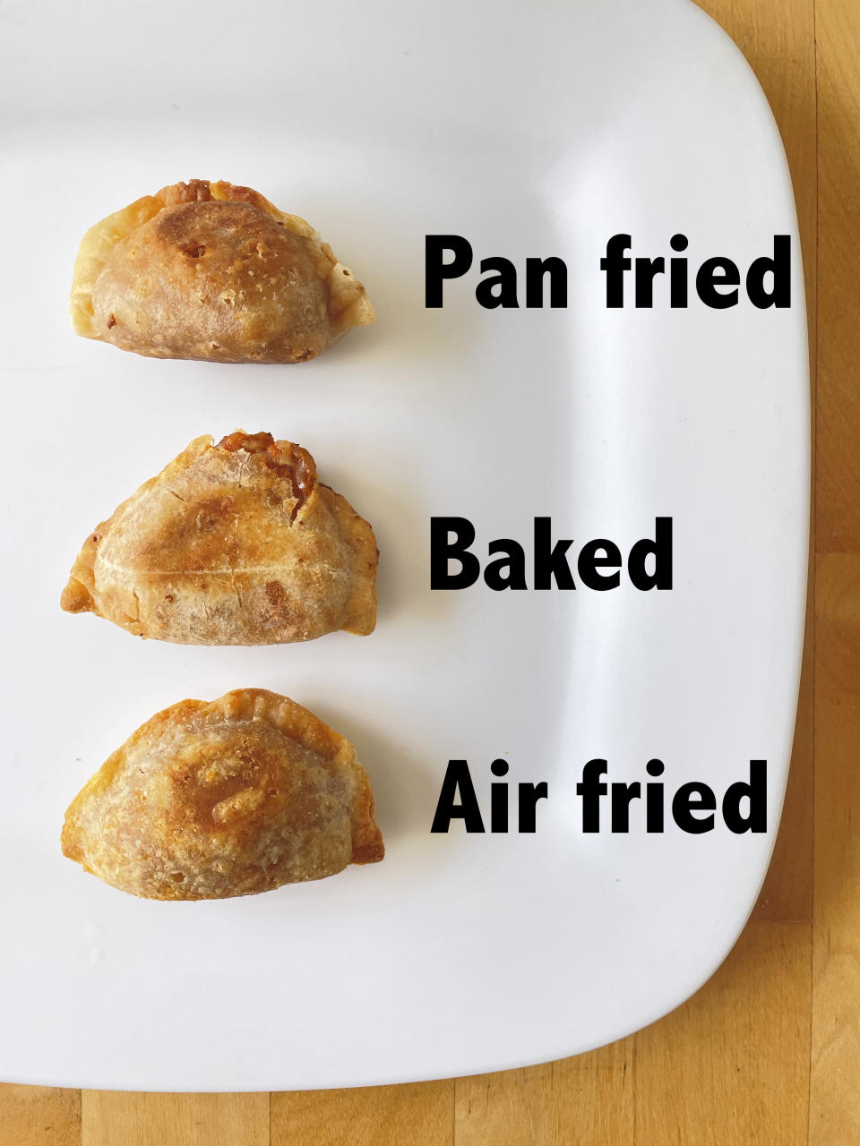 Three empanadas on a plate with the words "pan-fried," "baked," and "air fried" next to them