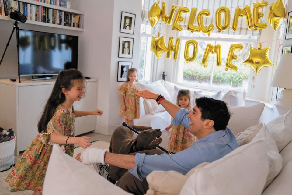 Journalist Benjamin Hall is welcomed home by his daughters Honor, far left, Iris and Hero, as well as their dog, Bosco.