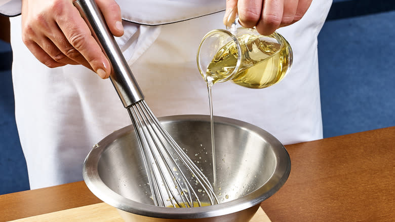 chef whisking stream of oil