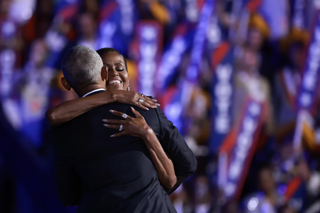 Former President Barack Obama hugs former first lady Michelle Obama onstage.