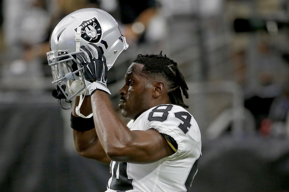 FILE - In this Aug. 15, 2019, file photo, Oakland Raiders wide receiver Antonio Brown (84) puts on his helmet prior to the team's NFL football game against the Arizona Cardinals in Glendale, Ariz. Brown missed significant practice time dealing with frost-bitten feet suffered while getting cryotherapy treatment in France and waging a battle with the NFL over the use of his outdated helmet. He lost a grievance to allow him to use the helmet that's no longer certified as safe and returned to camp. (AP Photo/Rick Scuteri, File)