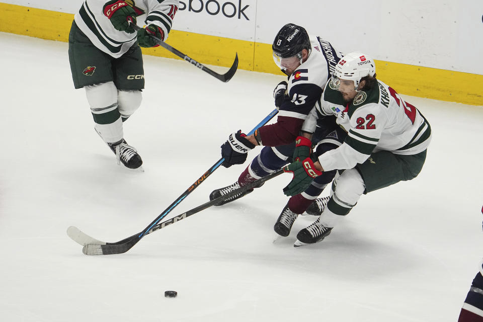 Colorado Avalanche right wing Valeri Nichushkin (13) and Minnesota Wild center Marat Khusnutdinov (22) fight for the puck in the third period of an NHL hockey game Tuesday, April 9, 2024, in Denver. (AP Photo/Bart Young)