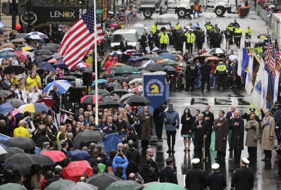 Sobrevivientes, funcionarios, socorristas e invitados observan el izamiento de bandera en la línea de meta durante la conmemoración del primer aniversario del atantado con explosivos realizado durante el maratón de Boston, el martes 15 de abril de 2014, en Boston. (Foto AP/Charles Krupa)