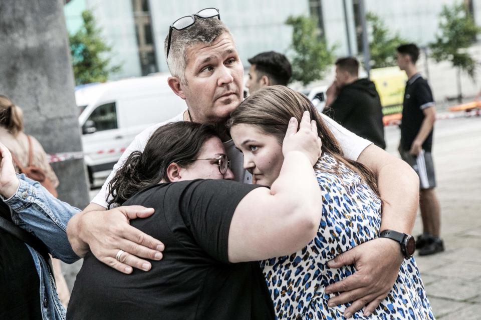 People hug each other in front of the Fields shopping mall, where a gunman killed three people on Sunday (Ritzau Scanpix/AFP via Getty Ima)