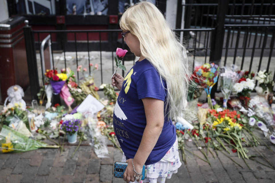 Mourners bring flowers to a makeshift memorial Tuesday, Aug. 6, 2019, for the slain and injured in the Oregon District after a mass shooting that occurred early Sunday morning, in Dayton. (AP Photo/John Minchillo)