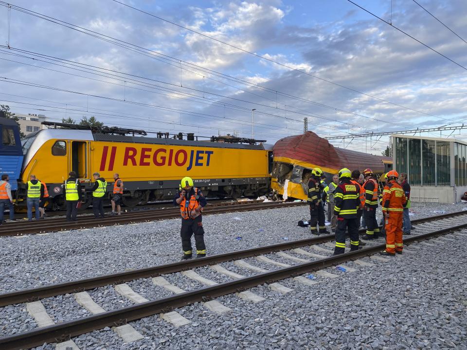 Firefighters stand by two trains that collided in Pardubice, Czech Republic Thursday, June 6, 2024. A passenger train collided head-on with a freight train in the Czech Republic, killing and injuring some people, officials said early Thursday. (AP Photo/Stanislav Hodina)