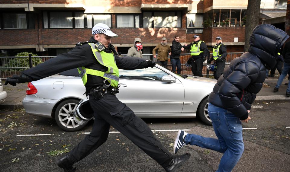 A police officer chases a man through streets close to the 'National March For Palestine' in central London on November 11, 2023, as counter-protest groups are monitored by police close to the route of the main march. Britain's Prime Minister Rishi Sunak has described a planned march in London on Saturday -- Armistice Day, when Britain honours its war dead -- as 