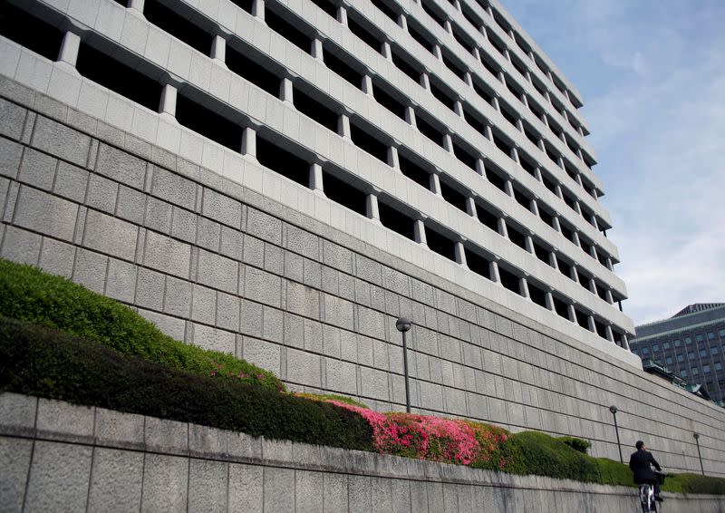 Man riding bicycle rides past the Bank of Japan building in Tokyo